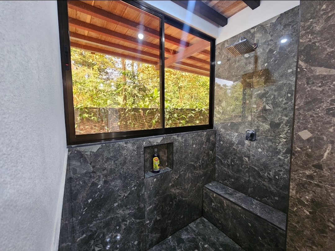 Marble walk-in shower with jungle view window