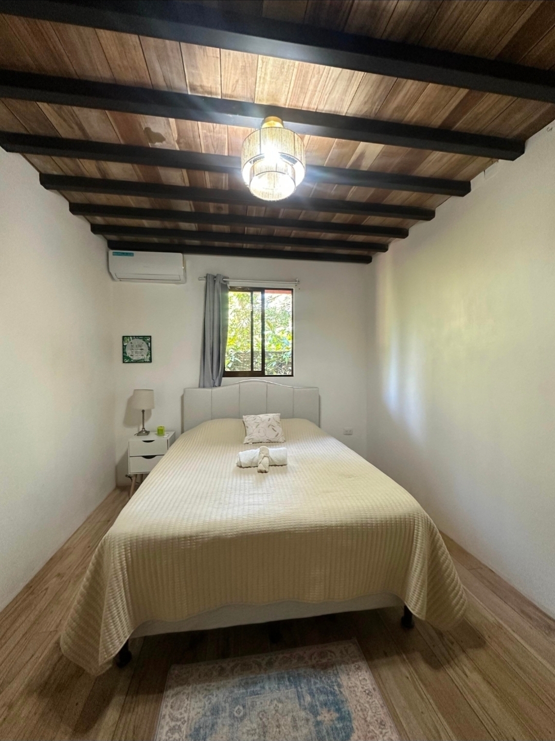 VIP room with queen bed, air conditioning, and wooden beam ceiling