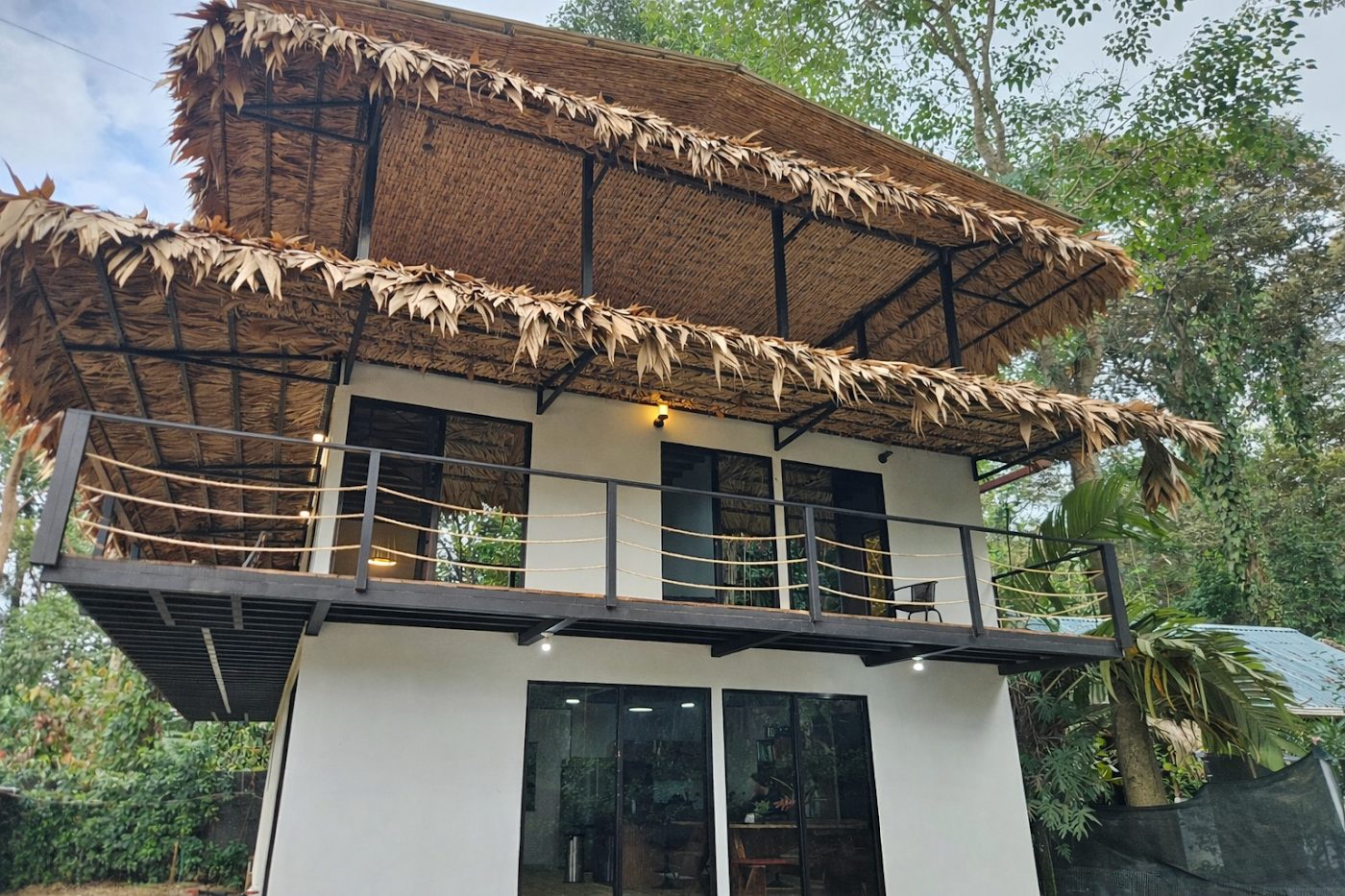 Two-storey main casa with thatched roof surrounded by jungle